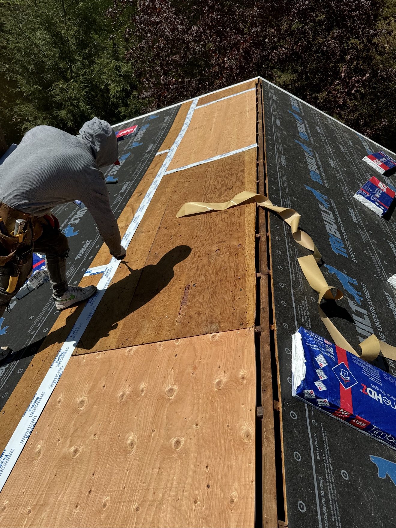Roofing crew installing synthetic underlayment on a Connecticut roof deck